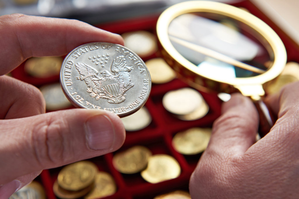 American dollar in hands of numismatist and magnifying glass